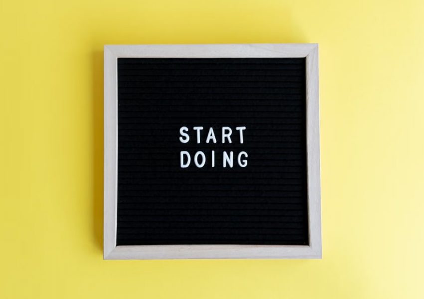 Black message board with 'Start Doing' on a bright yellow background for inspiration.